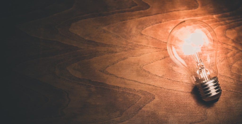 a lit lightbulb on a wooden table