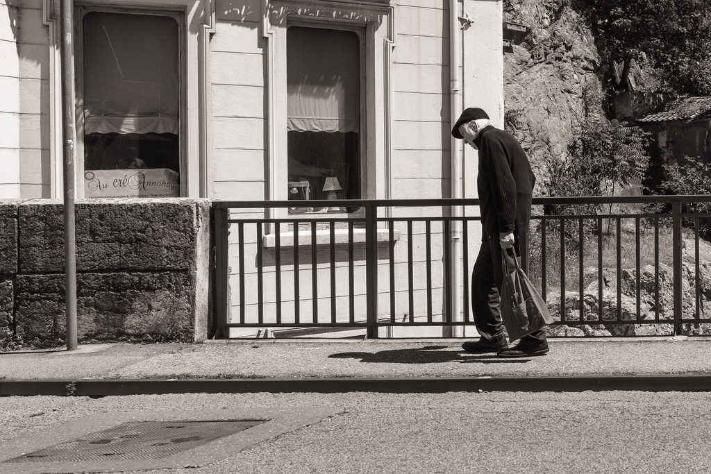 elderly man walking down sidewalk