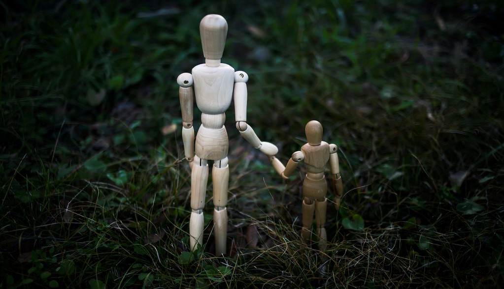 two wooden figurines holding hands