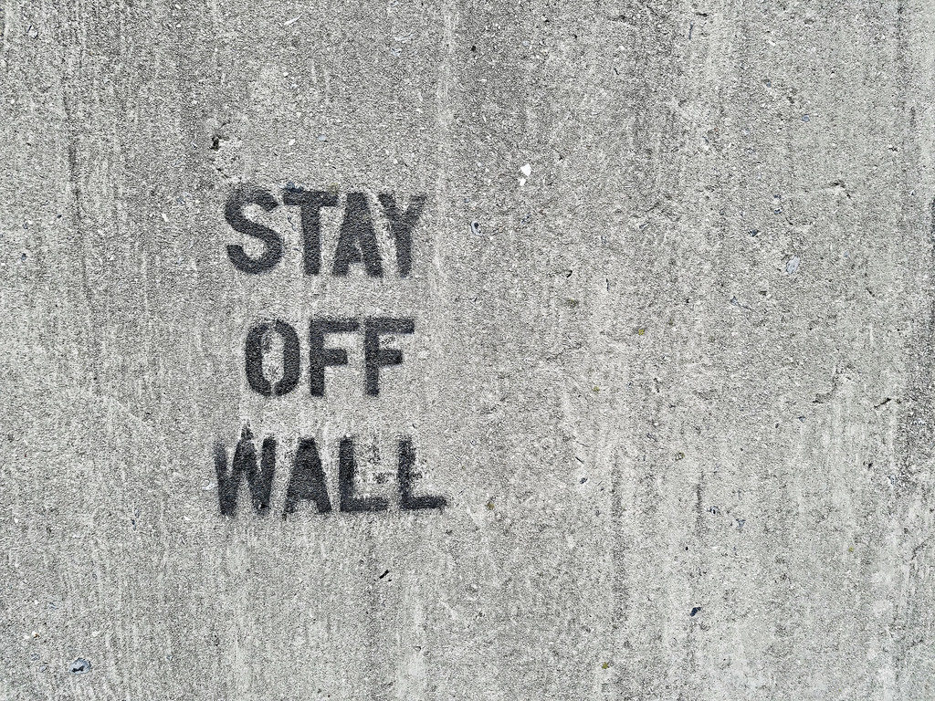a cement wall w/ "stay off wall" spray painted on it