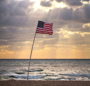 United States Flag in sand by ocean