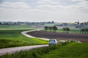 white car driving down an open road